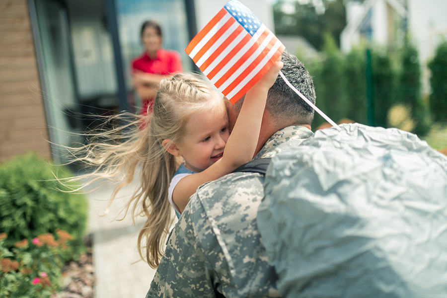 Daughter holding little American flag hugging daddy tight ATI Mission Impact