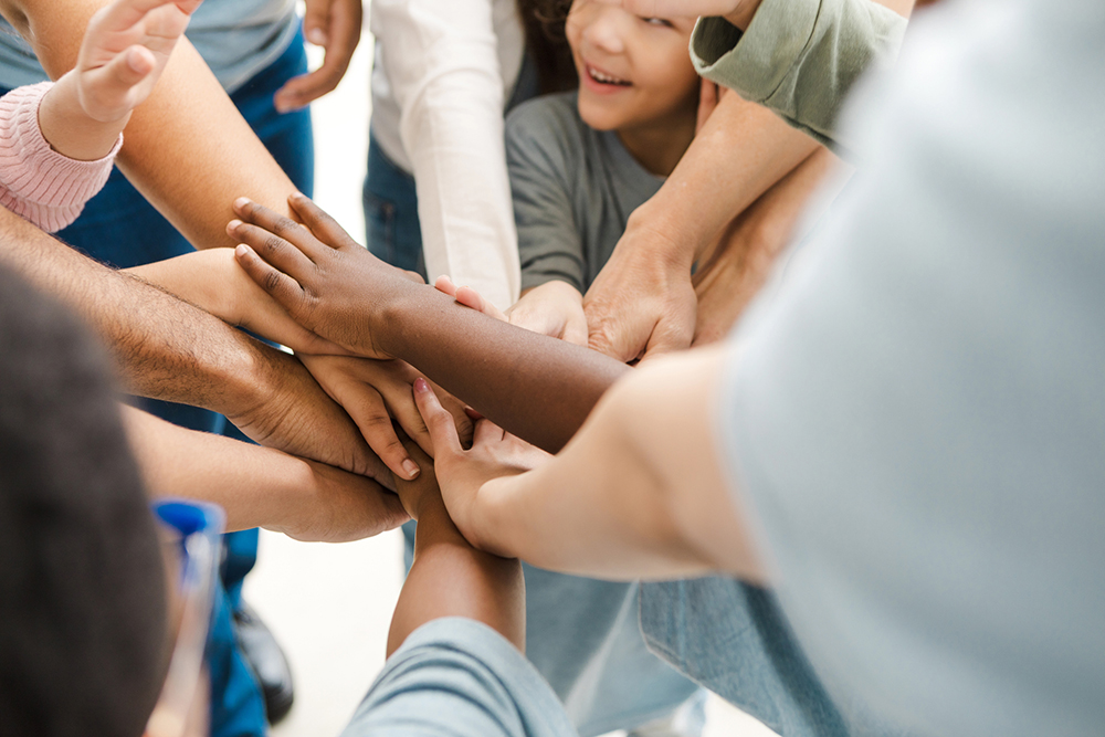 Multiracial Group of People Stacking Hands, Teamwork Concept ATI Corporate citizenship program